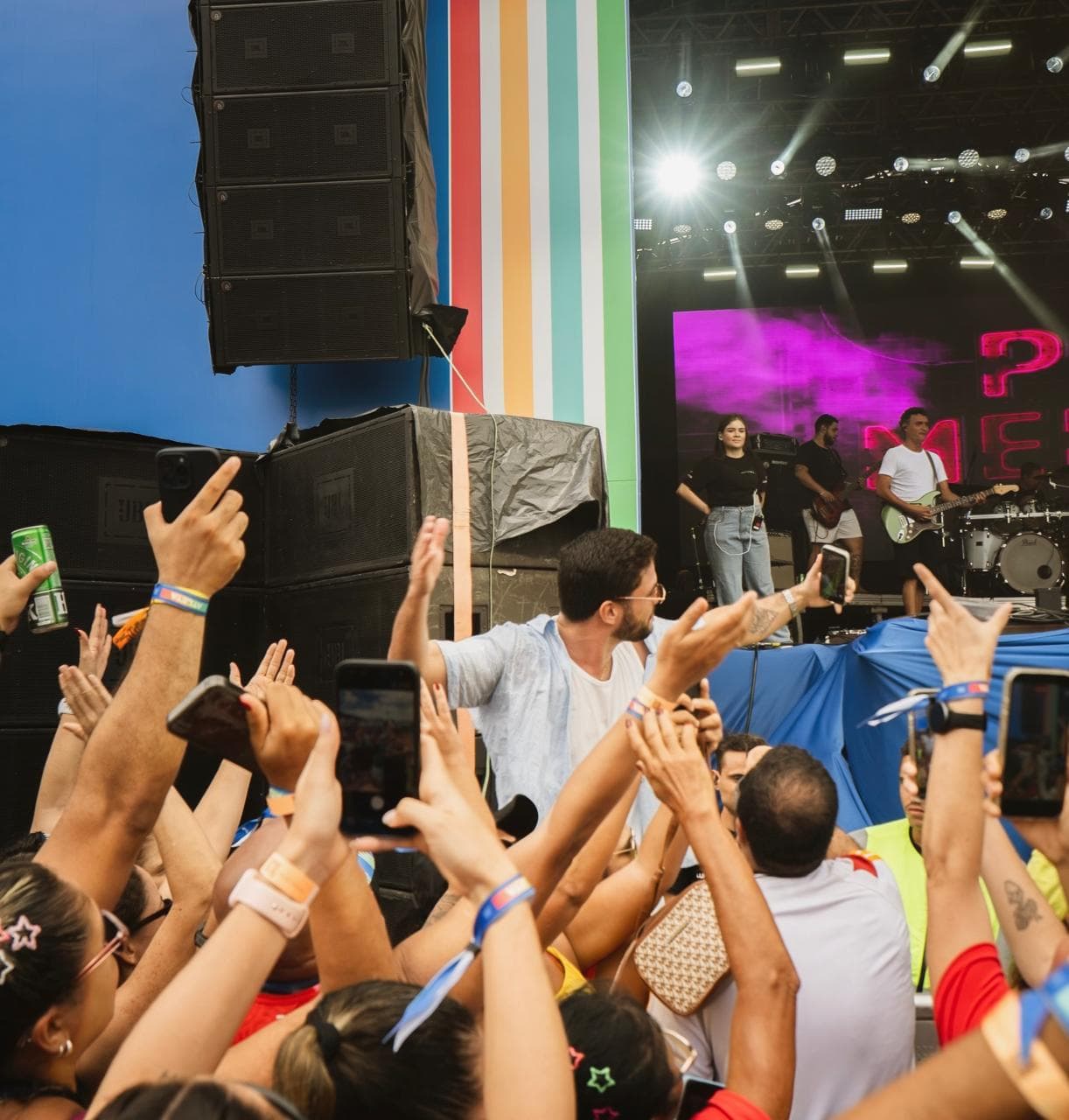 PV Mello no meio do público durante um show, com o palco e o letreiro PV Mello ao fundo